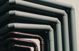Sistema de tuberías de agua potable instaladas en el exterior de un edificio, con canalización moderna y materiales plásticos y metálicos.